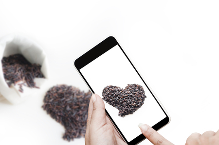Thai jasmine black rice or rice berry in white sack and pile of heart shape on white background.の写真素材