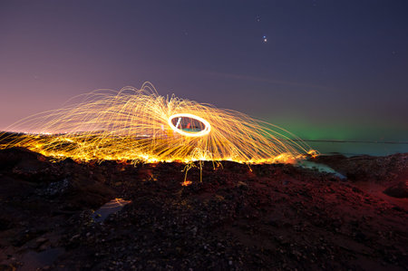 Showers of hot glowing sparks from spinning steel wool on the beach