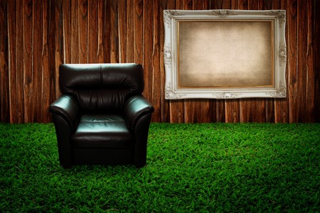 Leather sofa on green grass and photo frame against wooden wallの写真素材