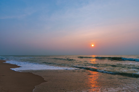 Gentle ocean waves on the sandy beach and morning sun