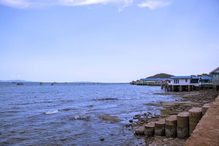 Fishing boats and seaside villages with blue skies and mountains behindの写真素材