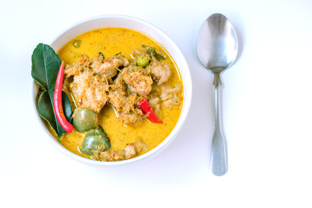Green curry with fish balls is a spicy Thai food. In a bowl on a white background