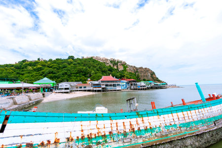 Fishing boat and a seaside fishing village with mountains behind at Khao Sam Mook, Chon Buri Provinceの写真素材