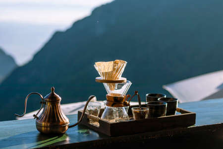Drip coffee set on wooden table with mountain view in the backgroundの写真素材