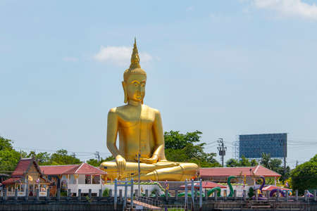 A large golden Buddha image sits along the Chao Phraya River at Wat Bang Chak in Nonthaburi Province in Thailand.のeditorial素材
