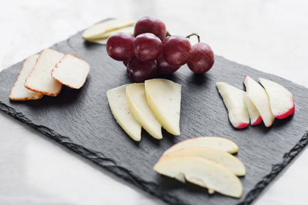 gourmet mixed cheese board tapas starter with apple and grapes snackの写真素材