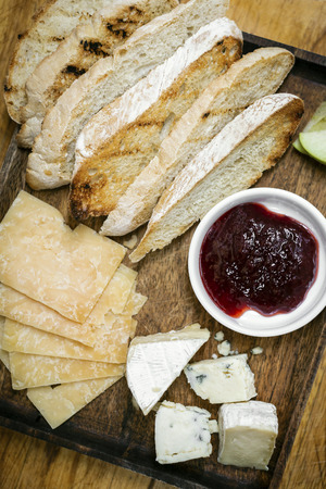 rustic mixed cheese board platter with toasted bread and redcurrant jam on wooden trayの写真素材