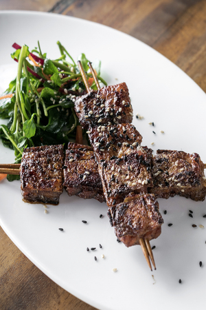 asian spicy sweet soy sauce and sesame seed grilled barbecue pork skewers in singapore restaurantの写真素材