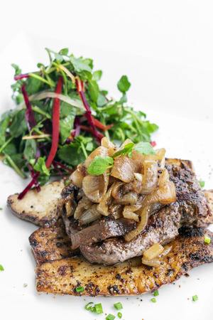 beef steak with grilled  mushrooms and caramelized onions gourmet meal on white plateの写真素材