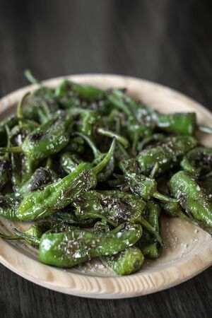pimientos padron grilled spanish green chilli peppers tapas snack on plate in rustic santiago de compostela restaurantの写真素材