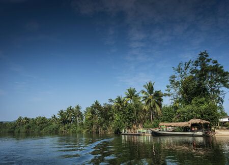 traditional jungle ferry boat at pier on tatai river in cambodiaのeditorial素材