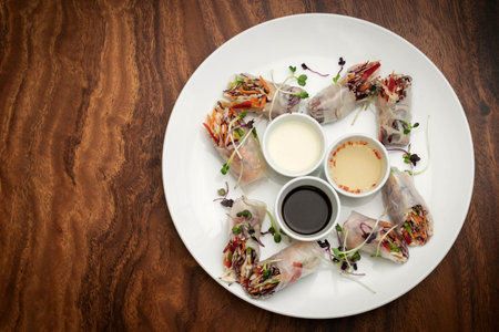 asian fresh vegetable vegan spring rolls with sauces on wood restaurant table in hanoi vietnam