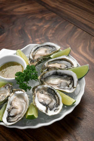 Six fresh oysters with lime wedges and citrus vinaigrette sauceの写真素材