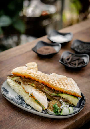 vegan roasted vegetable toasted panini sandwich in rustic garden table setting outdoors in sicilyの写真素材