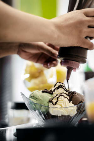 detail of staff making italian gelato ice cream sundae in modern shopの写真素材