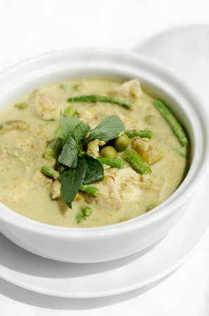 thai green curry with chicken and vegetables on white table background