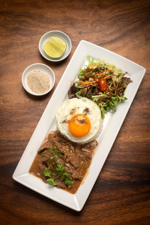 Traditional cambodian Lok Lak stir fried beef with rice meal on wood table background