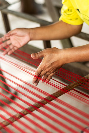 worker hands detail with traditional natural silk making machine strings
