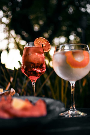 Mixed cocktail drinks and sangria with seafood snacks on restaurant table outdoors at sunset