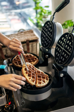 cafe worker making belgian waffles with modern professional machine