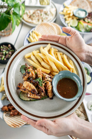 mediterranean style grilled squid with escabeche sauce and fries on white table at ibiza spain...