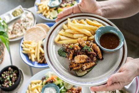 mediterranean style grilled squid with escabeche sauce and fries on white table at ibiza spain...