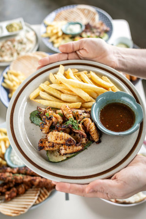 mediterranean style grilled squid with escabeche sauce and fries on white table at ibiza spain...