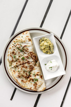 cheese quesadilla plate with guacamole and sour cream on white restaurant table in mexico