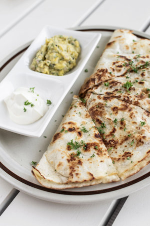 cheese quesadilla plate with guacamole and sour cream on white restaurant table in mexico
