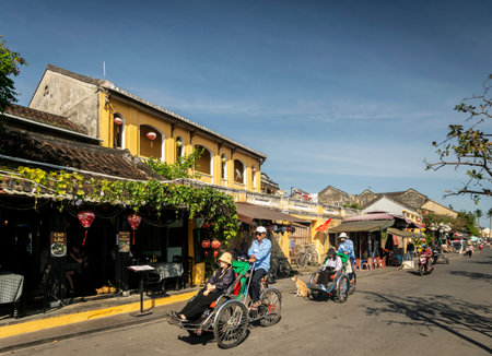 HOI AN, VIETNAM - FEBRUARY 8 2026: hoi an old town tourist area street with cyclo bicycle richshaws...