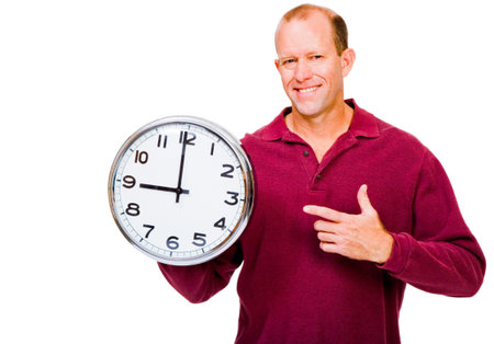Caucasian man showing a clock and smiling isolated over whiteの写真素材