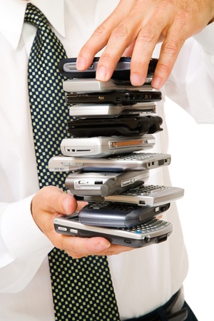 Close-up of a businessman holding a stack of phones isolated over whiteの写真素材