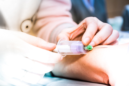 Medical person drawing blood with syringe and hypodermic needle from a patient.の写真素材