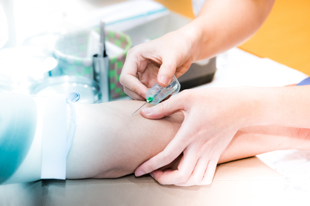 Medical person drawing blood with syringe and hypodermic needle from a patient.の写真素材