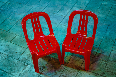 Two red chairs are placed in the middle of the market waiting for someone to sit.の写真素材
