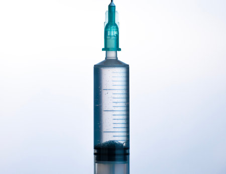 Syringe with clear liquid under studio lightingの写真素材