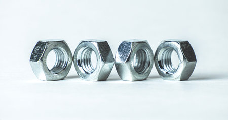 Four metallic nuts placed in a straight line showcasing their hexagonal shapes