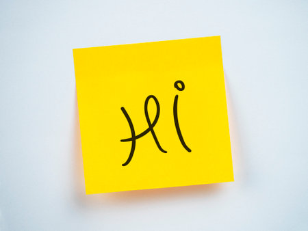 A bright yellow sticky note displays the word hi in a playful fontの写真素材