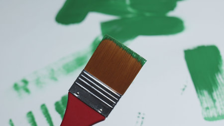 Painting with a green brush on a canvas in a bright studio. High quality photo
