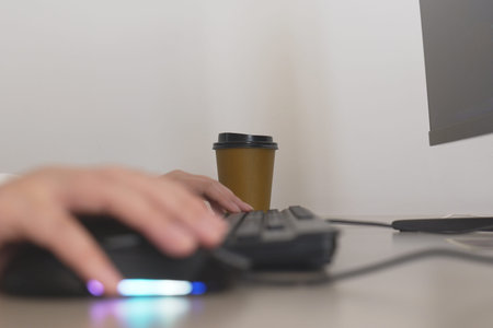 typing on a keyboard while a coffee cup sits nearby