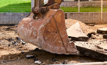 Heavy machinery lifts broken pavement at a residential area