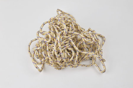 A tangled heap of rope lies on a plain white surface