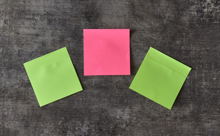Three sticky notes in pink and green sit on a dark backdrop