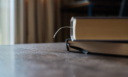 A bookmark is visible in a book resting on a wooden table indoors
