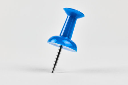 Close up of a blue pushpin placed on whiteの写真素材