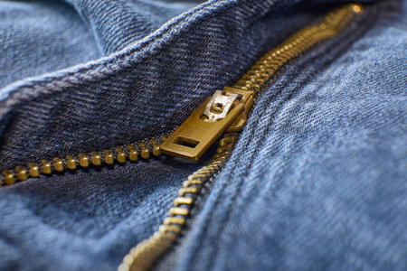 Golden zipper detail on a blue denim garment fabricの写真素材