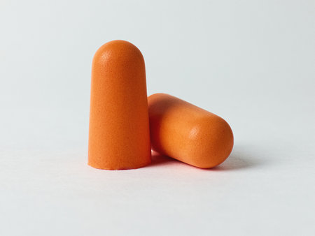 Two orange earplugs isolated on a flat surfaceの写真素材
