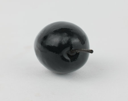 Single black olive resting on a plain surfaceの写真素材