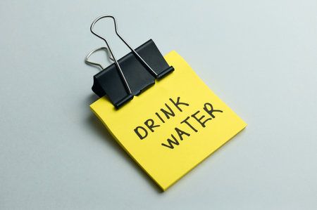 A bright yellow note with a reminder to drink waterの写真素材