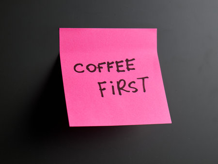 Bright pink sticky note emphasizes the need for coffee firstの写真素材